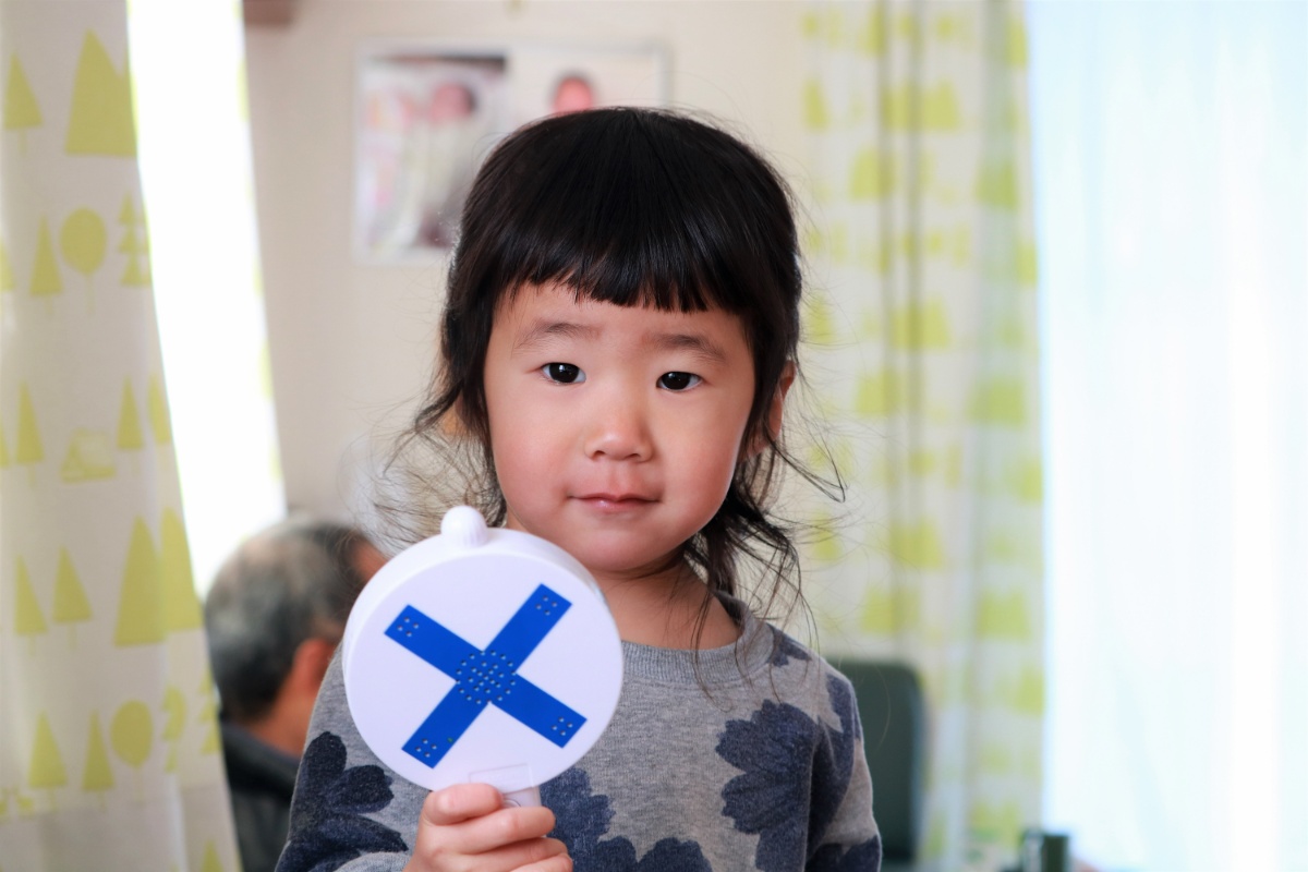 バツの書かれたプレートを持った子ども